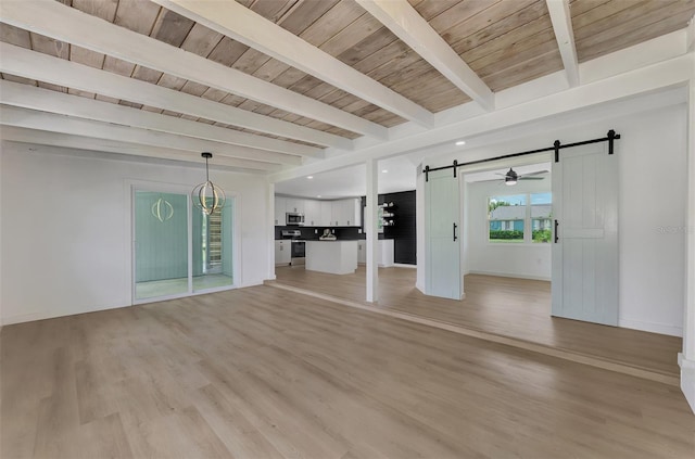 unfurnished living room with a barn door, wood ceiling, light hardwood / wood-style floors, and beam ceiling