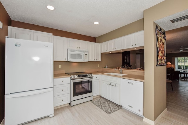 kitchen featuring a sink, white cabinetry, white appliances, light wood finished floors, and light countertops