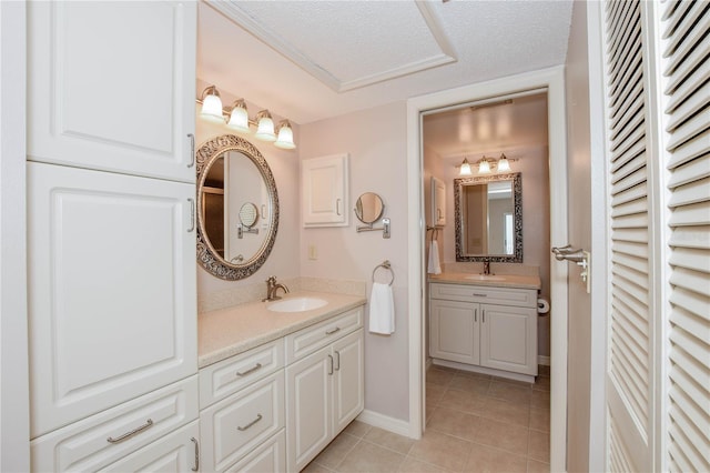 bathroom with vanity, baseboards, a closet, a textured ceiling, and tile patterned floors