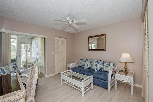 living area with baseboards, a textured ceiling, and a ceiling fan