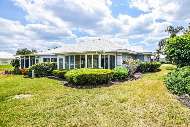 rear view of house with a lawn and a sunroom