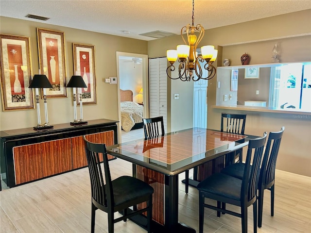 dining area featuring visible vents, a textured ceiling, and an inviting chandelier