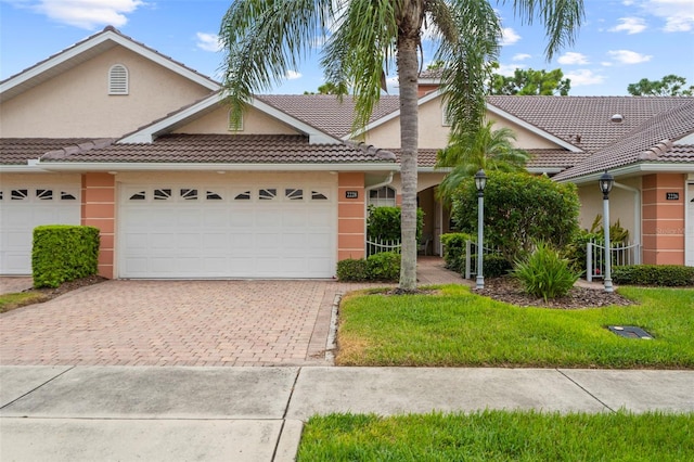 view of front of property featuring decorative driveway, a tile roof, an attached garage, and stucco siding