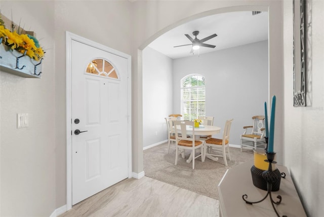 foyer with baseboards, visible vents, arched walkways, and a ceiling fan