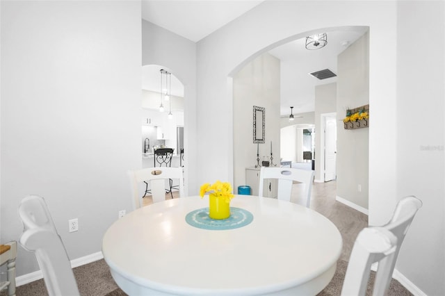 dining space with ceiling fan, baseboards, visible vents, and arched walkways