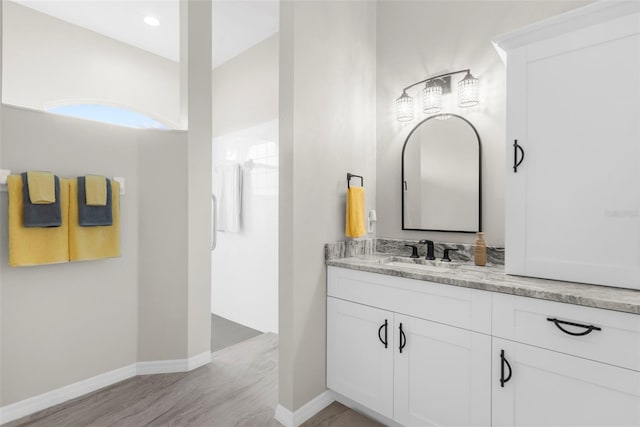 bathroom with recessed lighting, vanity, baseboards, and wood finished floors