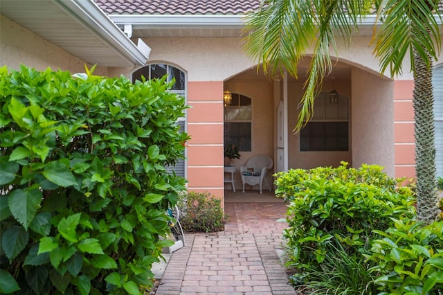 property entrance featuring a tile roof and stucco siding