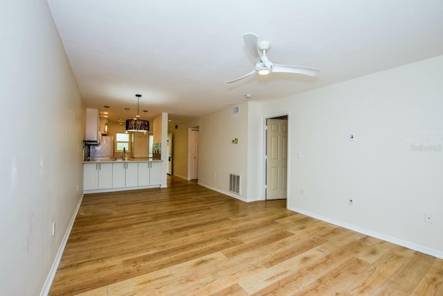 unfurnished living room with ceiling fan, sink, and light hardwood / wood-style flooring