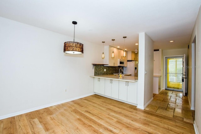 kitchen featuring kitchen peninsula, tasteful backsplash, pendant lighting, stainless steel fridge with ice dispenser, and light hardwood / wood-style floors