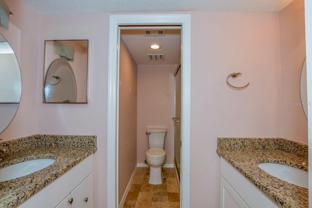 bathroom with vanity, a textured ceiling, and toilet