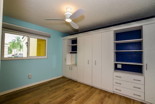 unfurnished bedroom featuring wood-type flooring, a textured ceiling, a closet, and ceiling fan