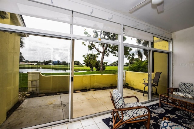 sunroom featuring ceiling fan and a water view