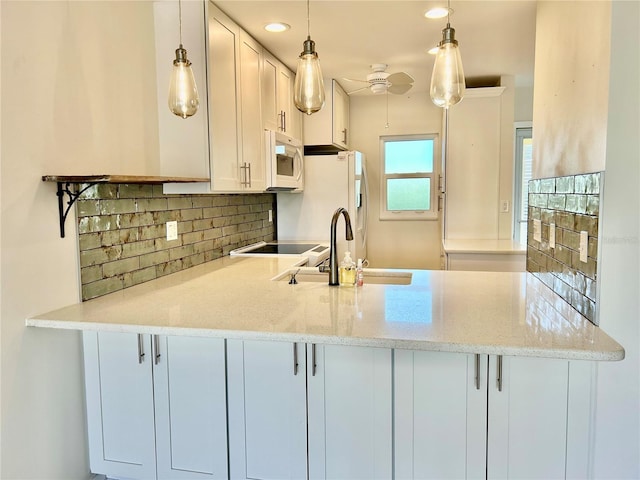 kitchen with white cabinets, decorative backsplash, light stone counters, and hanging light fixtures