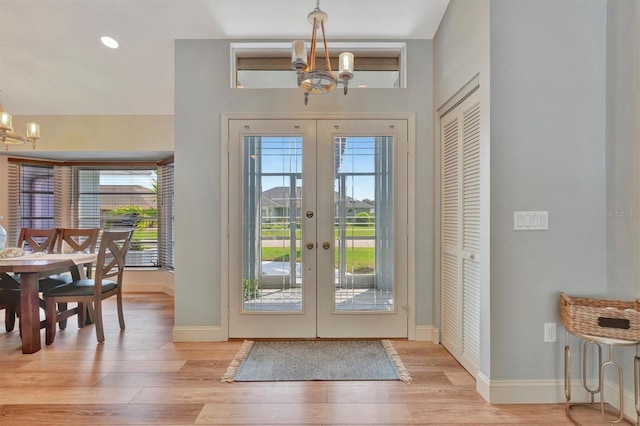 entrance foyer featuring light wood-type flooring, french doors, and a chandelier