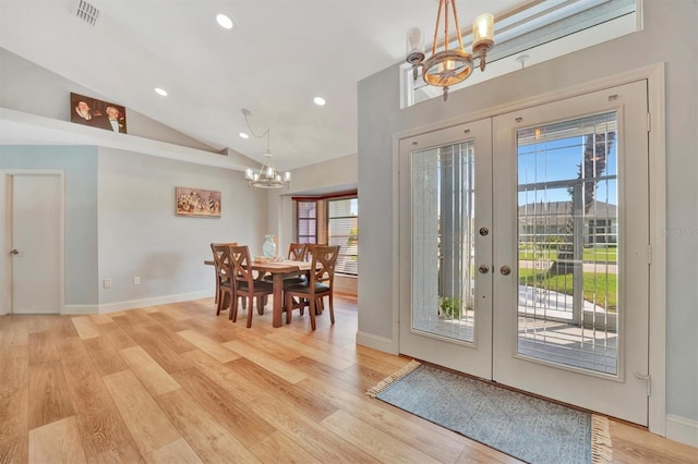 foyer entrance featuring light wood-type flooring, french doors, vaulted ceiling, and a notable chandelier