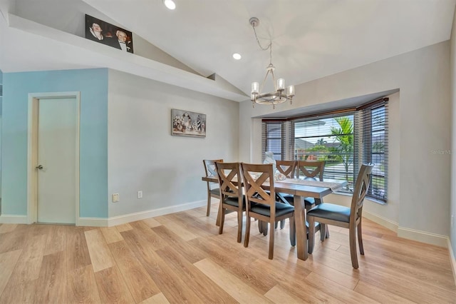 dining space with light wood-type flooring, a notable chandelier, and vaulted ceiling