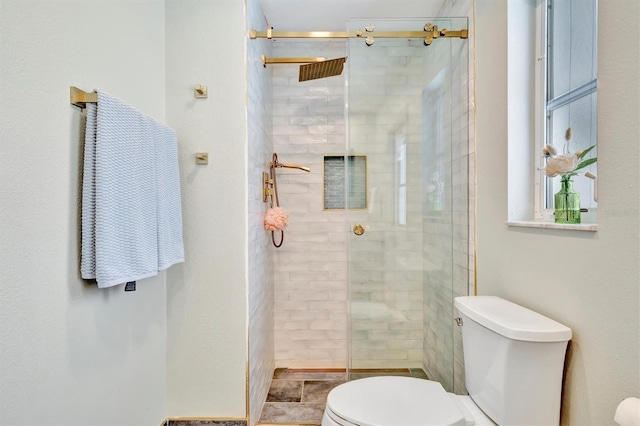 bathroom featuring a shower with shower door and toilet