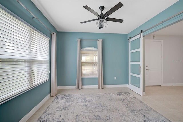 unfurnished room with a barn door and ceiling fan