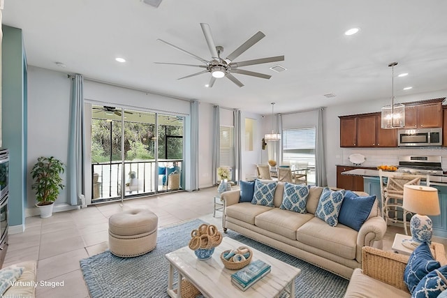 living room with light tile patterned floors and ceiling fan with notable chandelier