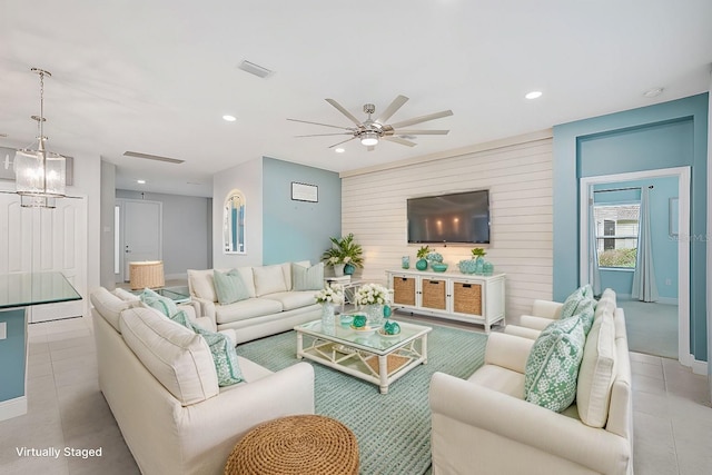 living room with ceiling fan with notable chandelier and light tile patterned floors