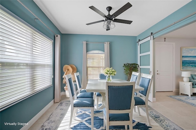 dining space featuring a barn door and ceiling fan