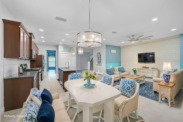 tiled dining area featuring sink, ceiling fan, and wood walls