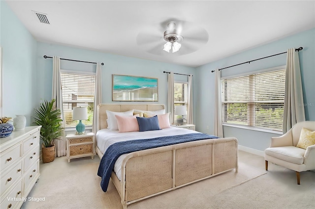 bedroom featuring ceiling fan, multiple windows, and light carpet