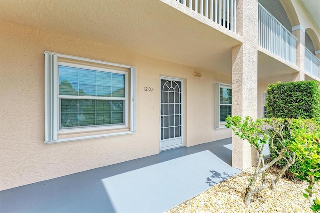 view of exterior entry featuring a balcony and a patio area