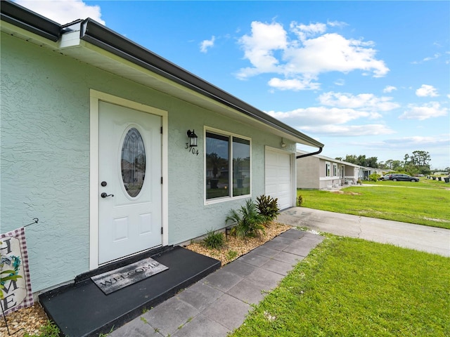 doorway to property with a garage and a yard