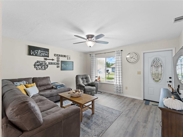 living room featuring light wood-type flooring, a textured ceiling, and ceiling fan