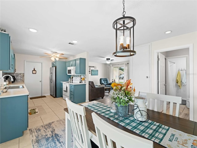 dining area with ceiling fan with notable chandelier, light tile patterned floors, and sink