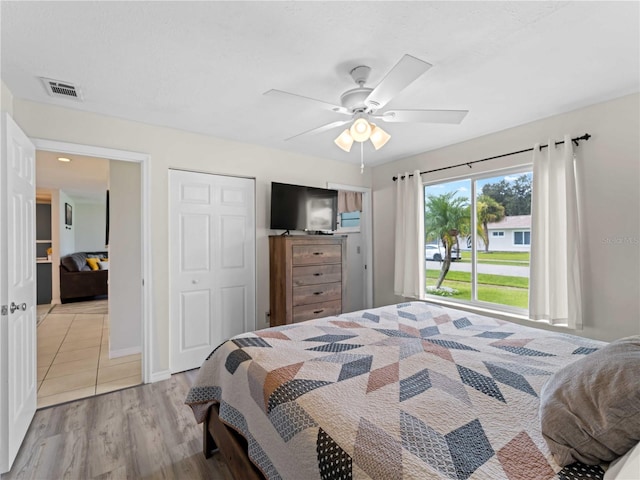 bedroom with light hardwood / wood-style floors, ceiling fan, and a closet