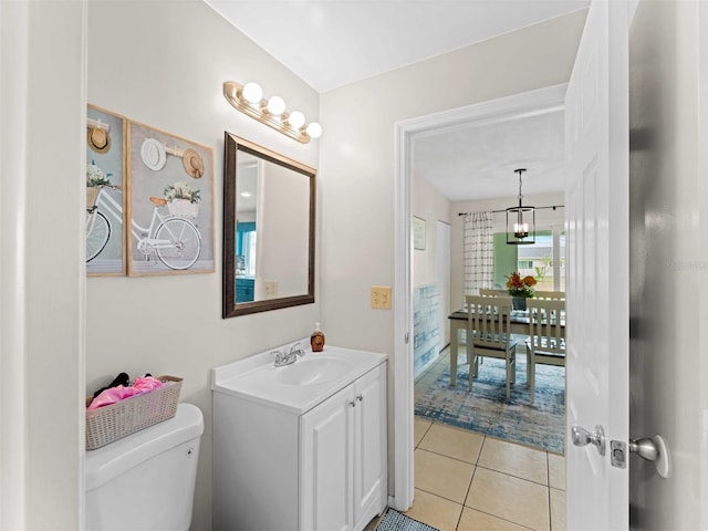 bathroom with a notable chandelier, vanity, tile patterned flooring, and toilet