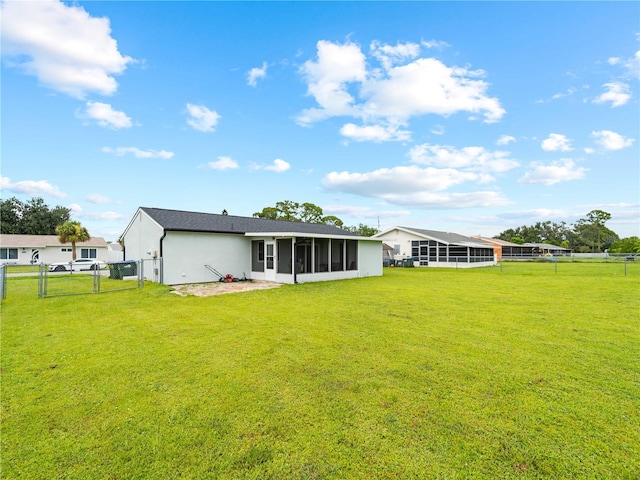 rear view of house with a yard and a sunroom