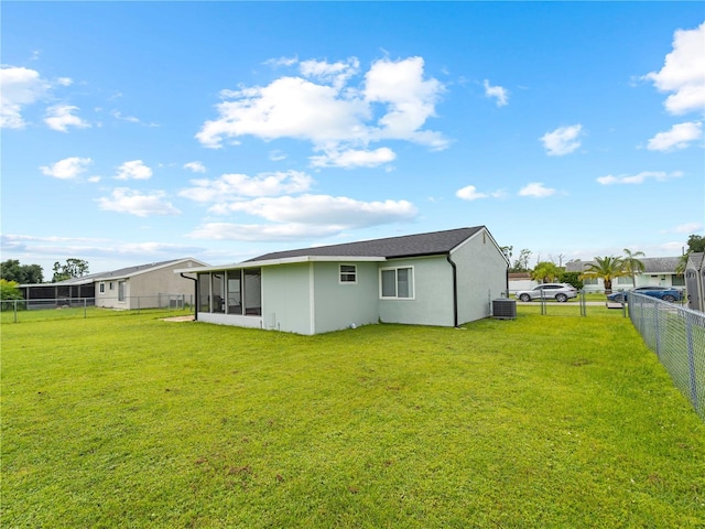 rear view of property featuring cooling unit, a sunroom, and a lawn