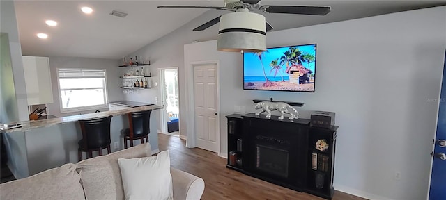 interior space featuring ceiling fan, a fireplace, wood-type flooring, and vaulted ceiling