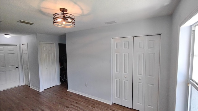 unfurnished bedroom featuring multiple closets, dark hardwood / wood-style flooring, and a textured ceiling