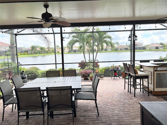 view of patio / terrace featuring a lanai, ceiling fan, a water view, and an outdoor bar