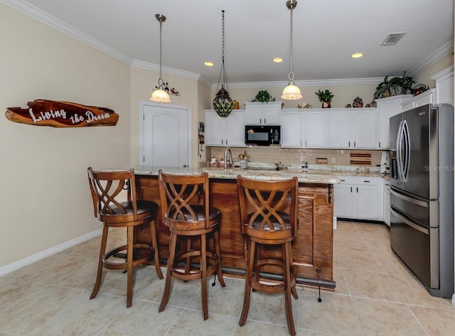 kitchen with tasteful backsplash, stainless steel refrigerator with ice dispenser, hanging light fixtures, and an island with sink