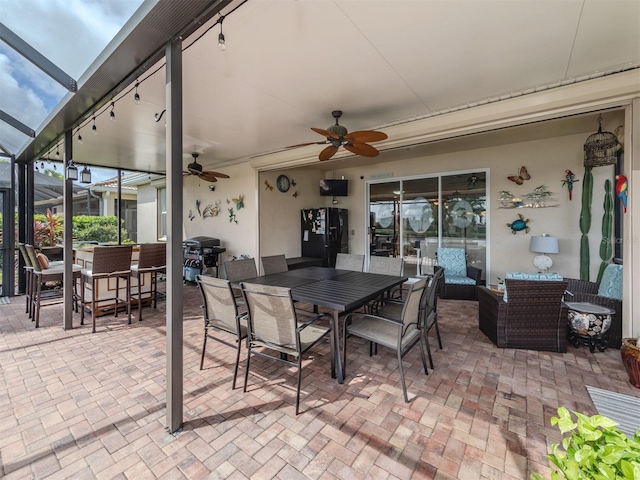 view of patio with a lanai, ceiling fan, a bar, and an outdoor hangout area