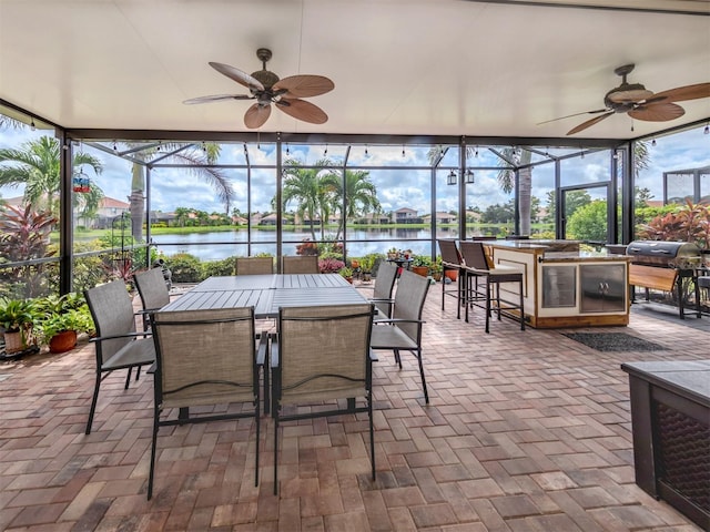 sunroom / solarium with a wealth of natural light, a water view, and ceiling fan