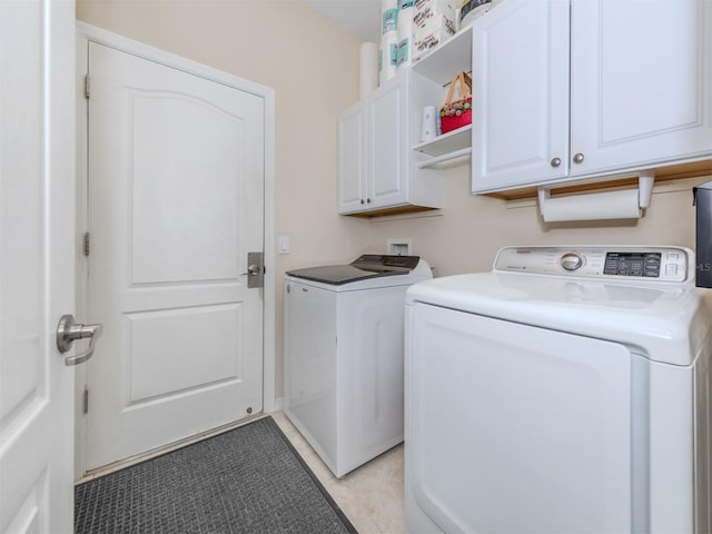 clothes washing area with cabinets, light tile patterned floors, and washer and clothes dryer