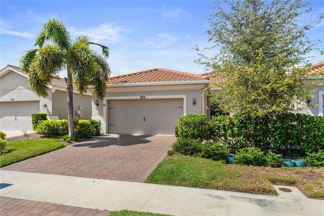 view of front of home with a garage, decorative driveway, a tile roof, and stucco siding