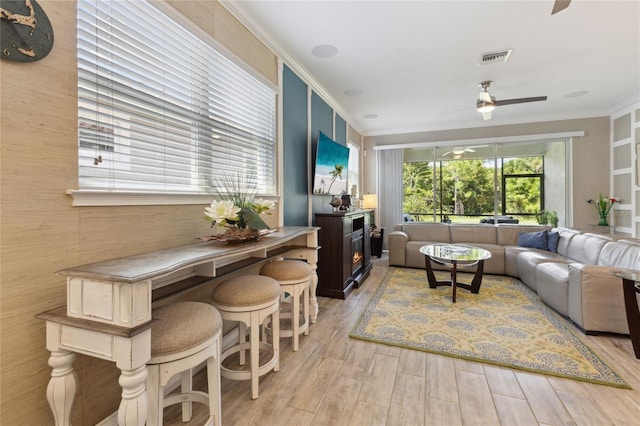 living room with ceiling fan, light wood-type flooring, and ornamental molding