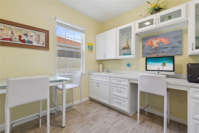 home office featuring light hardwood / wood-style flooring, built in desk, and sink