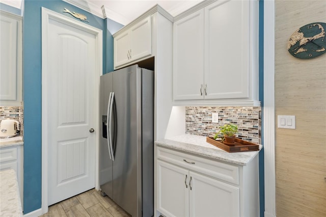 kitchen with white cabinets, light wood-type flooring, stainless steel refrigerator with ice dispenser, light stone countertops, and tasteful backsplash