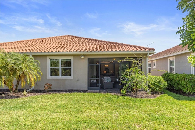 back of house featuring a lawn, a tiled roof, and stucco siding