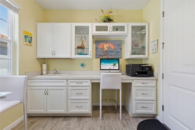 office featuring light wood finished floors, built in desk, plenty of natural light, and a sink