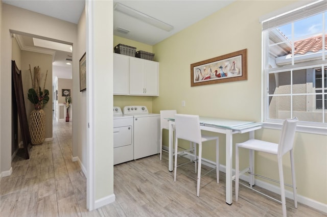 clothes washing area with washing machine and dryer, visible vents, baseboards, light wood-style floors, and cabinet space