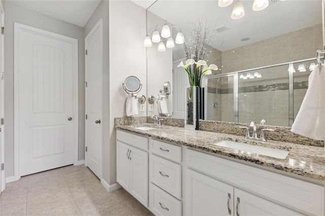 full bath with a stall shower, tile patterned floors, a sink, and double vanity